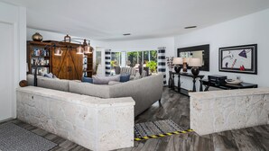 A modern living room with a sectional sofa, a stone accent wall, a wooden bookshelf, and a dining area with a table and chairs.