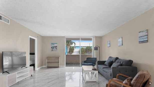 A modern living room with a flat-screen TV, a sofa, a coffee table, and a chair. - Bay Harbor Sunset Apt 2A (Bay Harbor Islands)