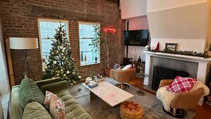 Ein gemütliches Wohnzimmer mit einem grünen Sofa, einem Couchtisch, einem Kamin und einem Weihnachtsbaum.