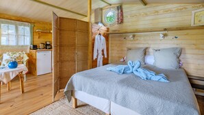 Eine Holzhütte mit einem Bett, einer kleinen Küchenzeile und einem Fenster mit Blick.