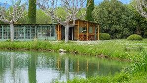 Eine Holzhütte mit Wintergarten, Teich und gepflegtem Garten.