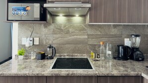 A modern kitchen with a built-in induction cooktop, a coffee maker, a blender, and a kettle. - Apartment Tlaquepaque | Panoramic View | Swimming Pool | Terrace | Gymnasium (San Pedro Tlaquepaque)