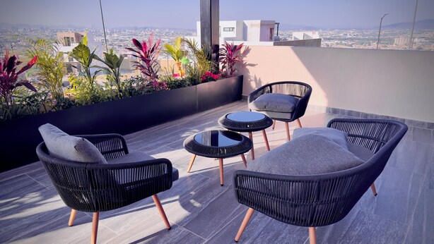 A rooftop terrace with wicker furniture, a small round table, and a view of the cityscape. - Apartment Tlaquepaque | Panoramic View | Swimming Pool | Terrace | Gymnasium (San Pedro Tlaquepaque)