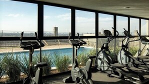 A gym with stationary bikes and a view of a swimming pool. - Apartment Tlaquepaque | Panoramic View | Swimming Pool | Terrace | Gymnasium (San Pedro Tlaquepaque)