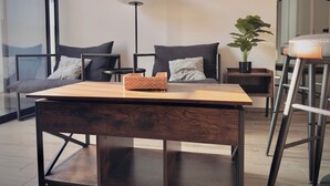 A modern living room with a wooden table, two armchairs, a floor lamp, and a potted plant. - Apartment Tlaquepaque | Panoramic View | Swimming Pool | Terrace | Gymnasium (San Pedro Tlaquepaque)