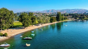 A lakeside view with boats, a sandy beach, and a park with trees. - Bright Water Sunrise Home at Wapato Point Resort 5-bed Close to Sandy Beach/Pool (Manson)