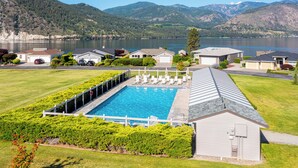 A residential area with a swimming pool, houses, and a lake with mountains in the background. - Bright Water Sunrise Home at Wapato Point Resort 5-bed Close to Sandy Beach/Pool (Manson)
