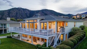 A two-story house with a balcony, a covered patio, and a view of a mountain. - Bright Water Sunrise Home at Wapato Point Resort 5-bed Close to Sandy Beach/Pool (Manson)