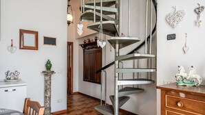 A spiral staircase with a metal finish, a wooden cabinet, a table with chairs, and a decorative vase. - Holiday Home 'Ruben' with Shared Pool, Private Terrace and Wi-Fi (Fucecchio)