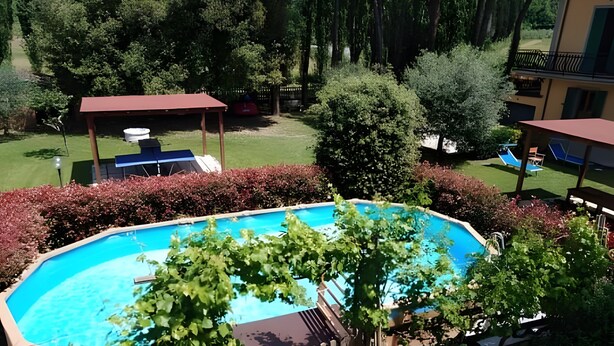 A swimming pool surrounded by a wooden fence, with a grassy area and trees in the background. - Holiday Home 'Ruben' with Shared Pool, Private Terrace and Wi-Fi (Fucecchio)