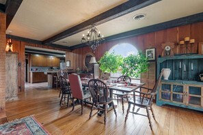 Un comedor con piso de madera, un candelabro y vistas al exterior.