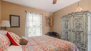 Ein Schlafzimmer mit einem Bett, einem Sessel, einem Kleiderschrank und einem Deckenventilator.