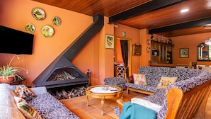 Uma sala de estar aconchegante com lareira, sofás estampados e uma televisão.