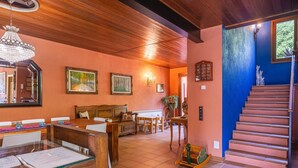 Um quarto espaçoso com teto de madeira, área de jantar com mesa e cadeiras, escada e parede azul.