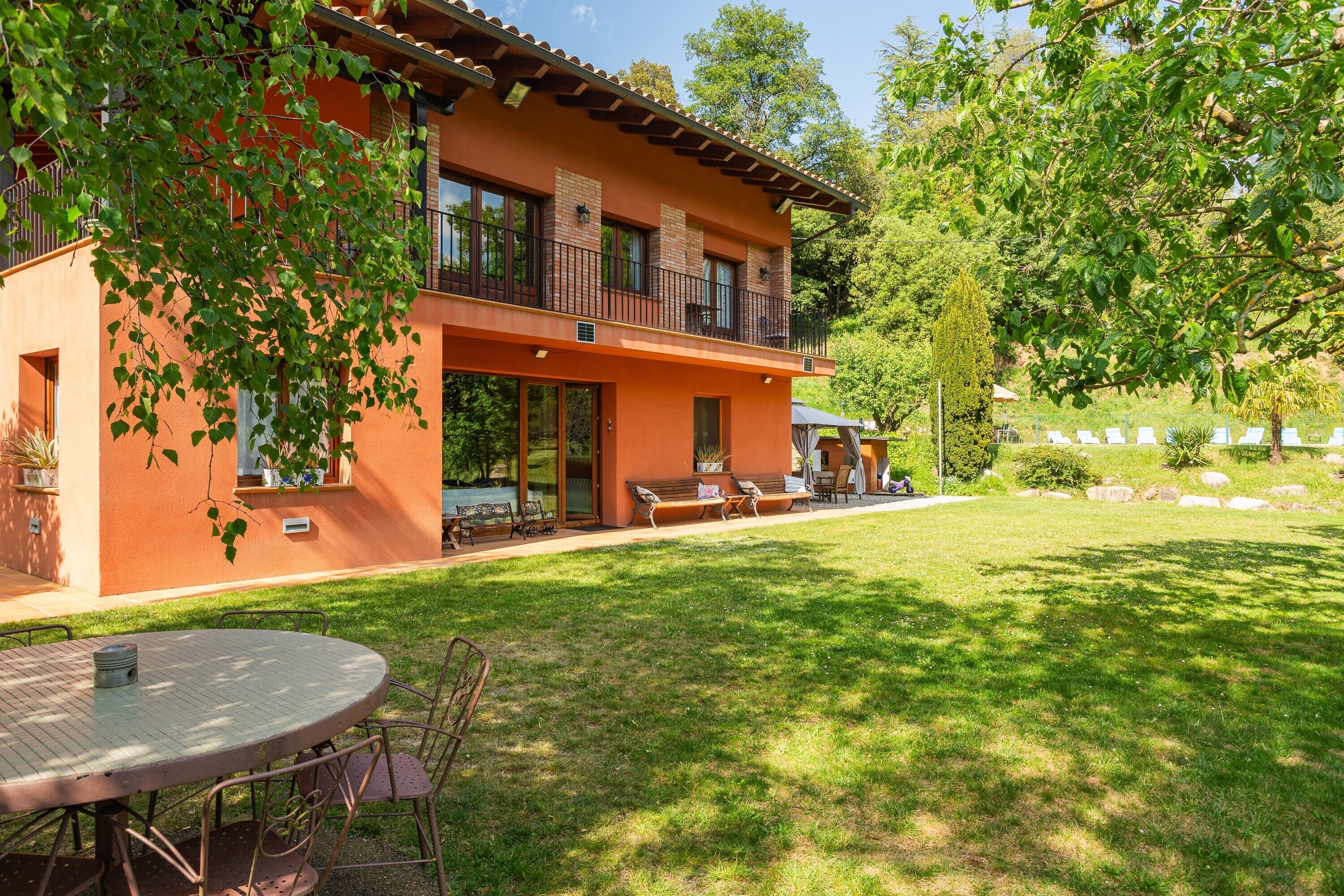 A two-story building with a balcony, a patio with seating, and a well-maintained lawn.