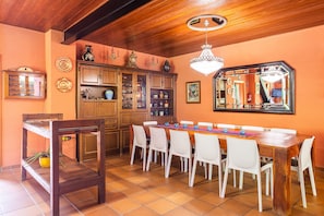 Comedor con mesa de madera, sillas blancas, candelabro y un espejo grande.
