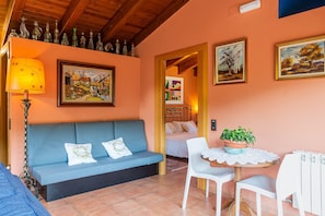 Una habitación acogedora con un sofá azul, una mesa con una planta en maceta y cuadros en las paredes.