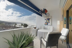 A balcony with a table and chairs, a potted plant, a decorative fish hanging from the ceiling, and a painting on the wall. - Vacation 'Merlin' with Sea View, Wi-Fi and Air Conditioning (Playa San Juan)
