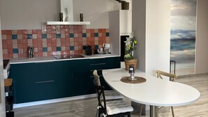 Une cuisine moderne avec des armoires de couleur turquoise, un plan de travail blanc et un pare-feu en carreaux.