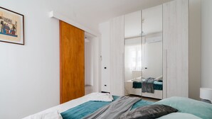 A bedroom with a bed, a wardrobe, a mirror, and a painting on the wall.