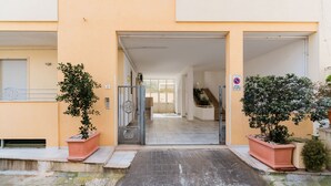 A building entrance with a gated driveway, potted plants, and a no parking sign.