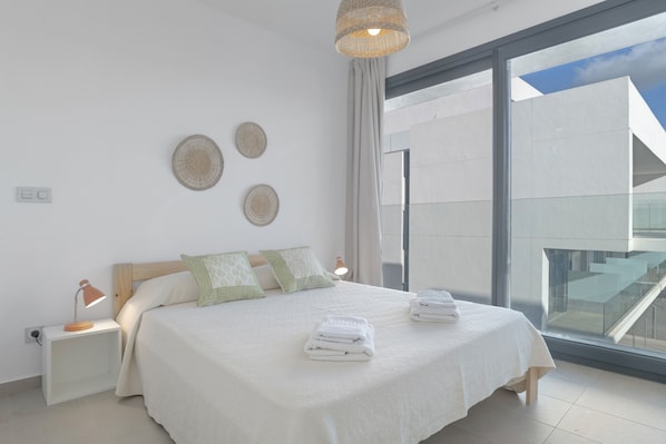 A modern bedroom with a large bed, bedside lamps, and a view of the outside.