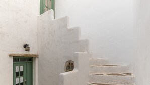 A narrow white-walled corridor with a green door and a small window.
