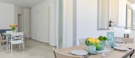 Ein moderner Essbereich mit einem Holztisch, weißen Stühlen und einer Glasvase mit Blumen.