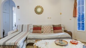 Une pièce comprenant un lit, une petite table, un élément décoratif mural et une fenêtre avec des rideaux.