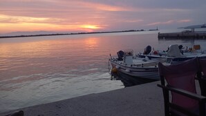 Une vue sur le bord de l’eau, avec des bateaux amarrés, un banc et un coucher de soleil paisible.