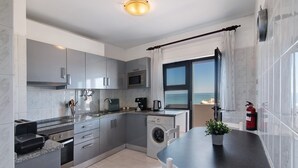 A modern kitchen with grey cabinets, a built-in oven, microwave, and dishwasher. There's a dining table with chairs and a potted plant. - Apartment '1 Bedroom Seaview' with Sea View, Wi-Fi and Air Conditioning (Unknown)