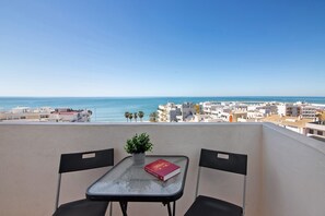 En balkon med et bord, to stole, en potteplante og en bog.