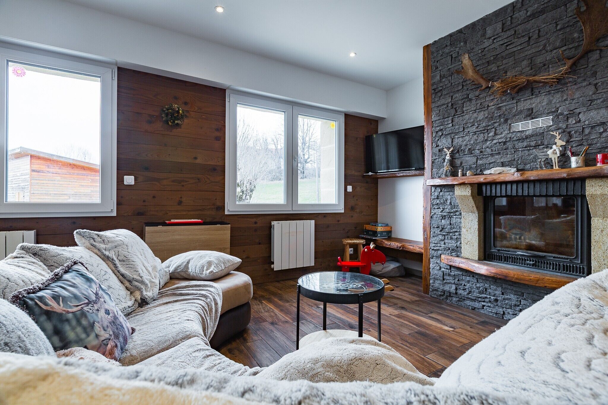 Una sala de estar acogedora con chimenea, paredes de madera y un sofá cómodo.