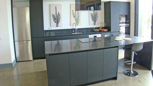 Een moderne keuken met een centraal eiland, roestvrijstalen apparatuur en een minimalistische inrichting.