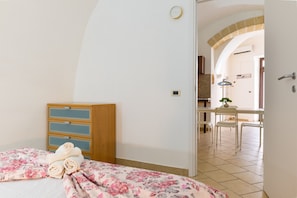 A bedroom with a bed, a wooden dresser, and a dining area with chairs and a table. - Apartment 'Sg  Family' with Air Conditioning (Massafra)