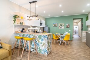 Une cuisine moderne dotée d’un îlot central, de tabourets de bar et d’un coin repas avec des chaises jaunes.