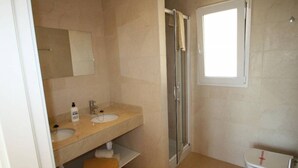 A bathroom with a sink, mirror, shower, and toilet. - Holiday Home 'Residence Club El Paraiso 30' with Sea View, Wi-Fi and Air Conditioning (Sa Ràpita)