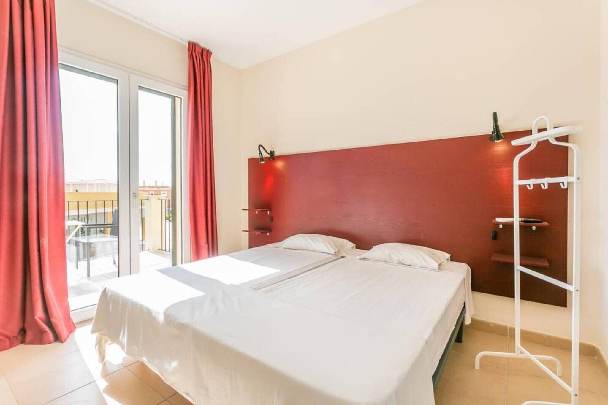 Ett hotellrum med en säng, ett vitt metallställ och utsikt över omgivningarna.