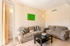 Un salon avec deux canapés, une table basse et un tableau abstrait vert accroché au mur.