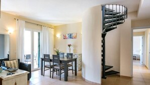 Una sala de estar moderna con comedor, una escalera en espiral y vistas al exterior.