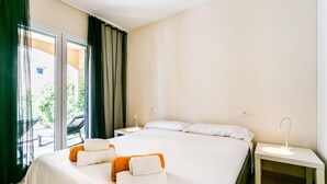 Una habitación de hotel con una cama, dos mesitas de noche, una ventana con cortinas y vistas al exterior.