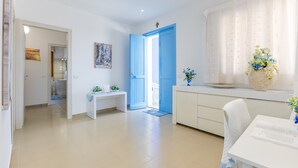 Une pièce moderne et bien éclairée, avec un bureau blanc, un banc et une porte donnant sur une autre pièce.