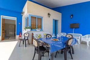 A dining area with a blue table, chairs, and a TV mounted on the wall.