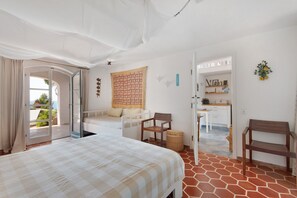 Ein Zimmer mit einem Bett, einem Sofa, einem Sessel, einem kleinen Tisch und einer Küchenzeile.