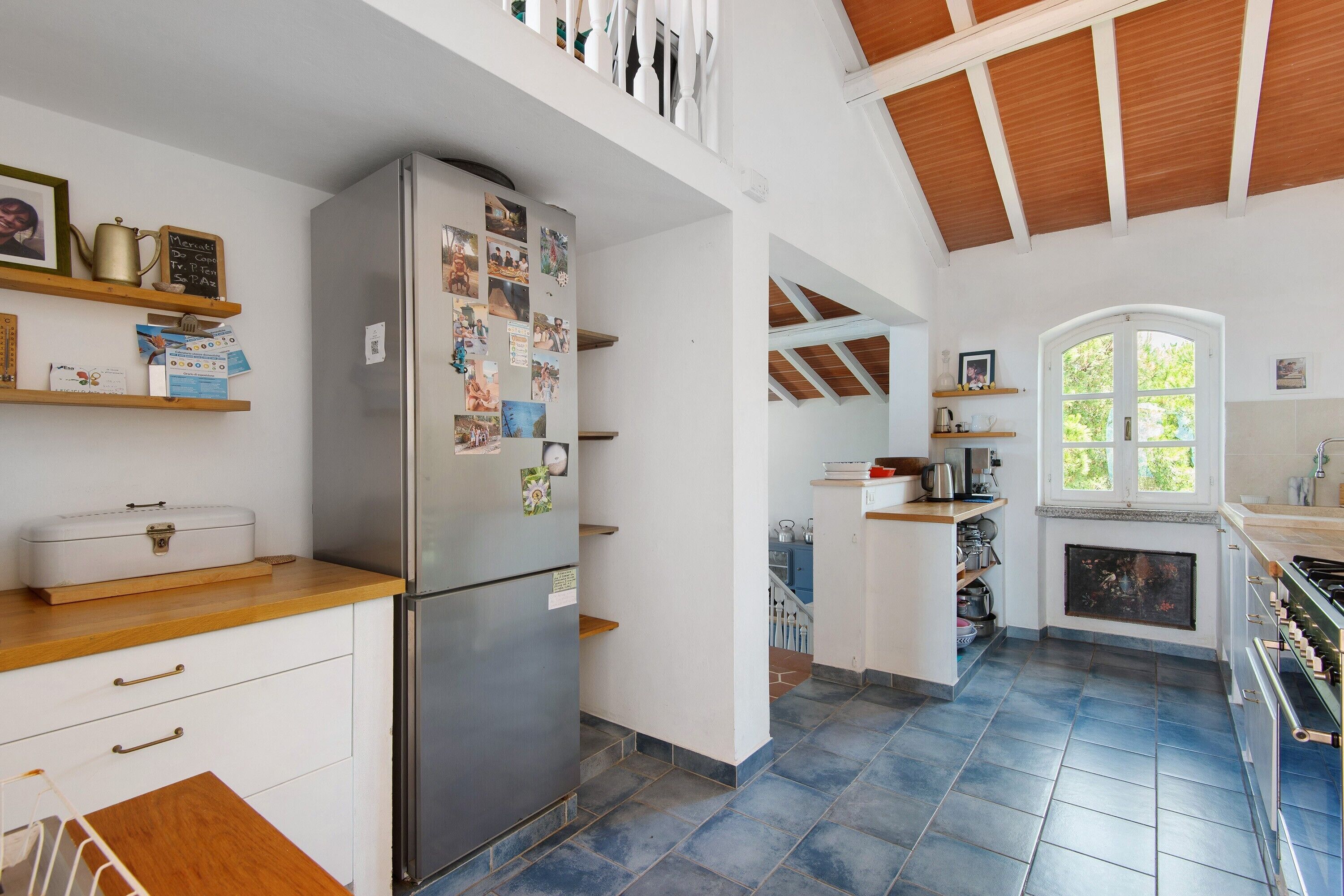 A kitchen with a refrigerator, wooden cabinets, and a tiled floor.