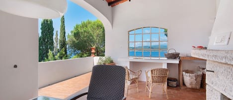 A patio with a table, chairs, a window with a view, and a brick floor.