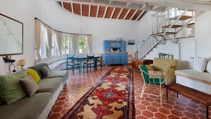 Un vaste espace de vie comprenant un canapé, une table à manger et un escalier.