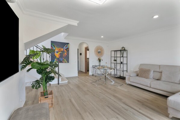 A modern living room with a staircase, a dining area, and a sofa.
