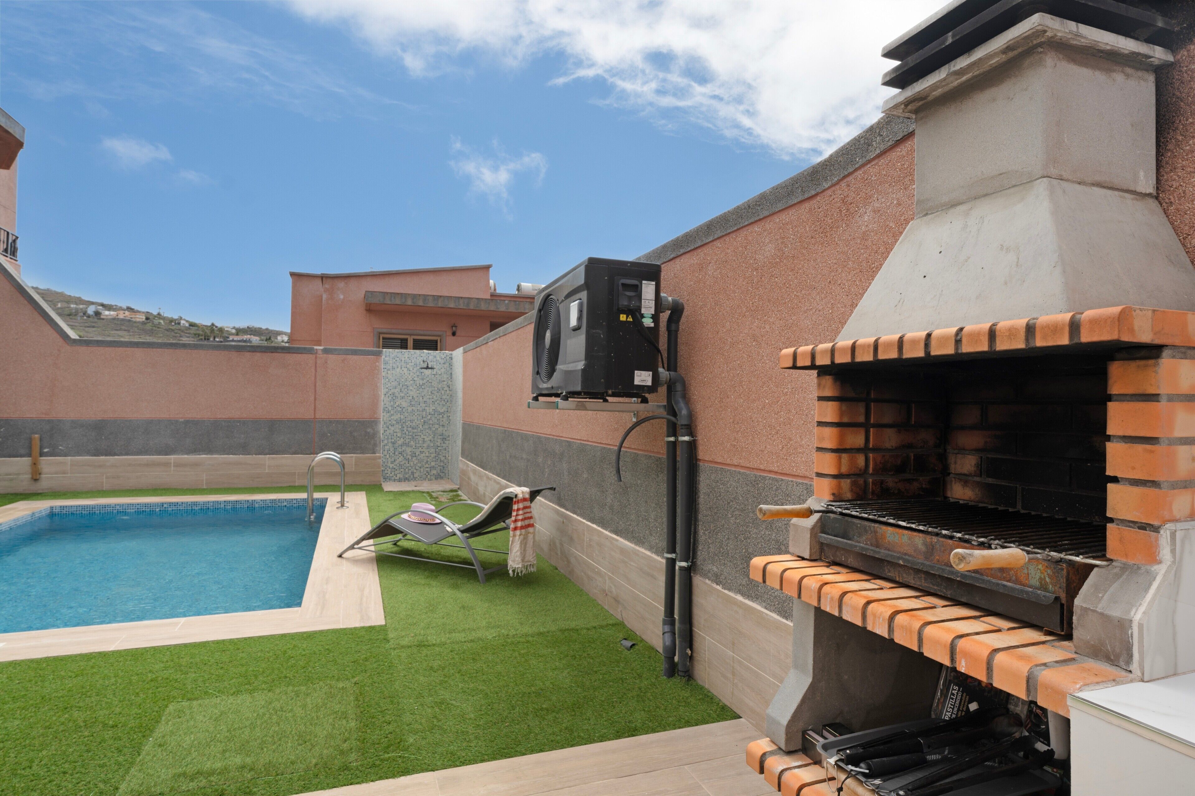Un jardin avec une piscine, un barbecue et un fauteuil de relaxation.