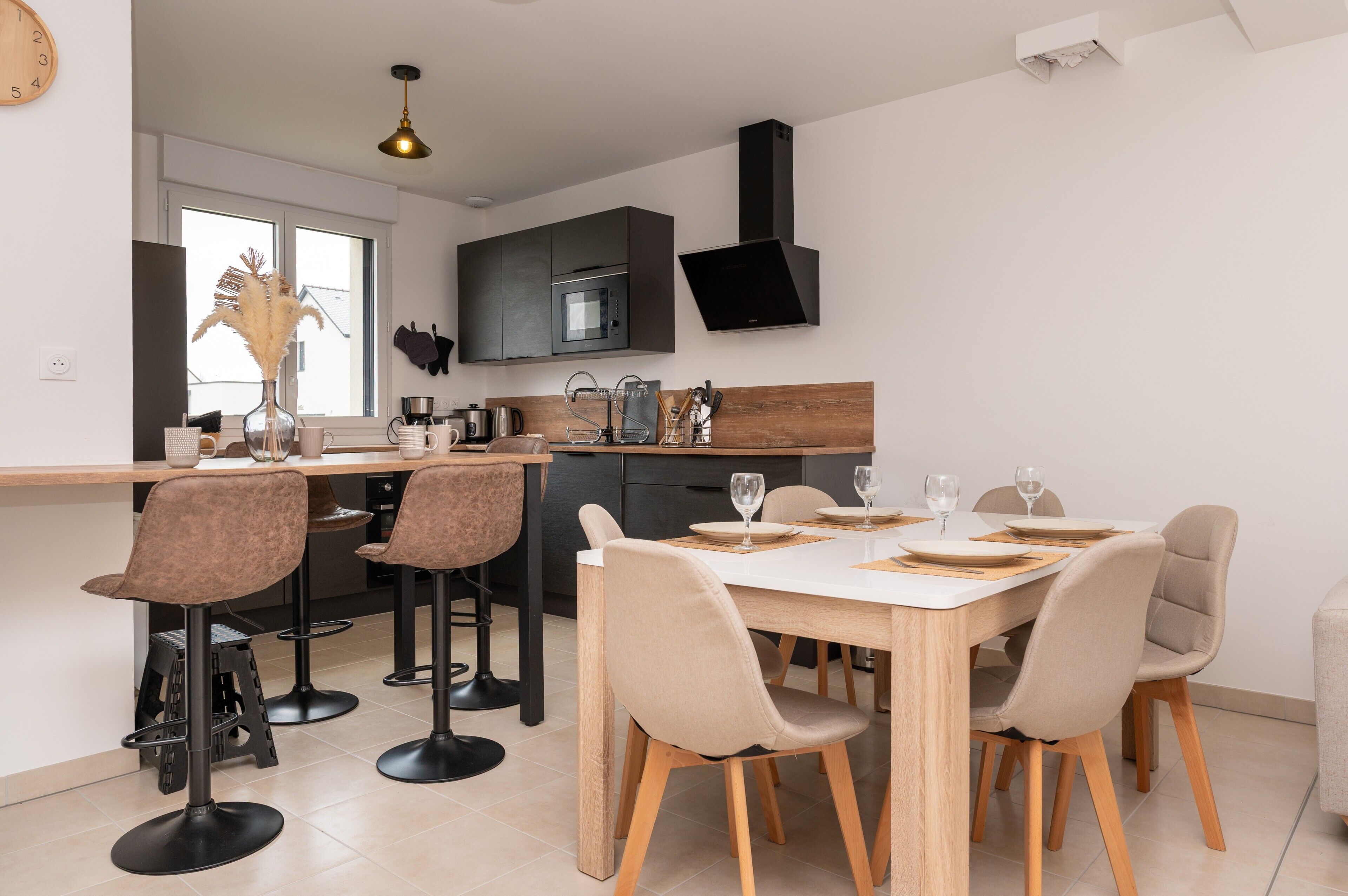 Una cocina moderna con una isla central, taburetes de bar y una mesa de comedor con sillas.